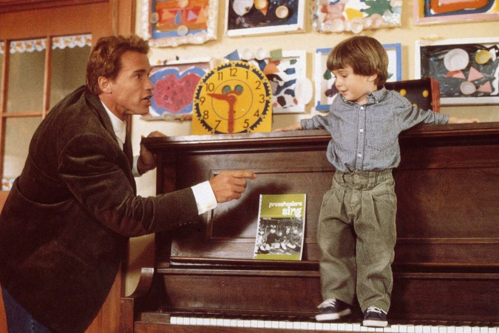 映画キンダガートンコップよりピアノの上に乗る子供とアーノルド・シュワルツェネッガー